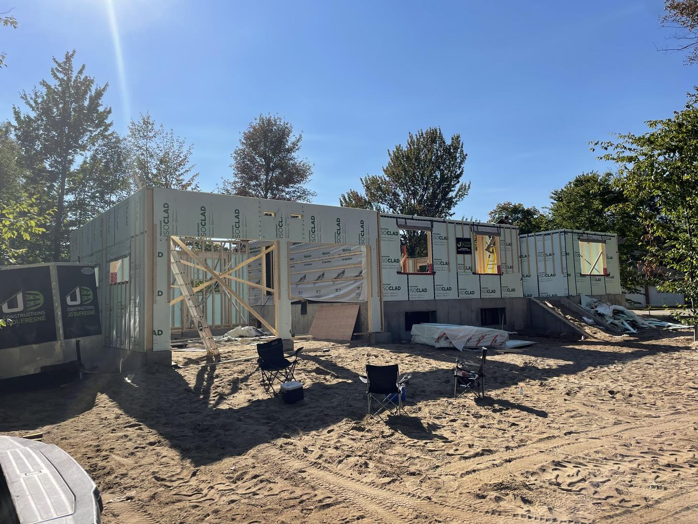 Chantier de construction : Ossature d'un bâtiment d'un étage avec isolation, fenêtres et terrasse.