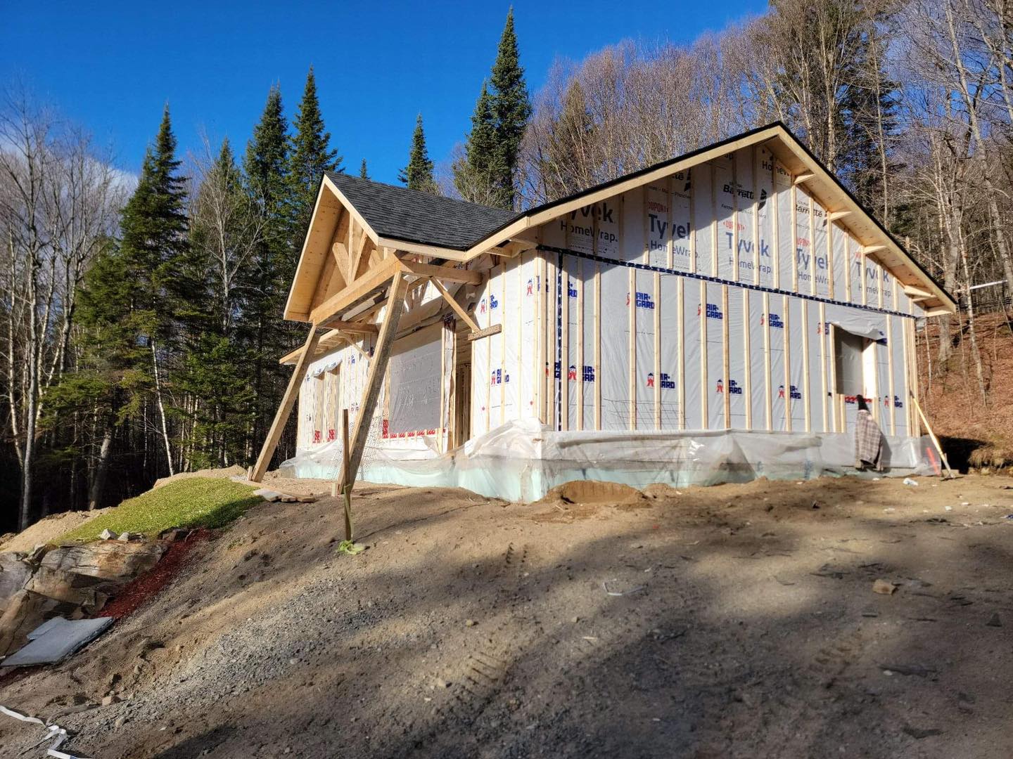 Construction d'une petite maison, à ossature bois et toiture apparentes, située à flanc de colline.