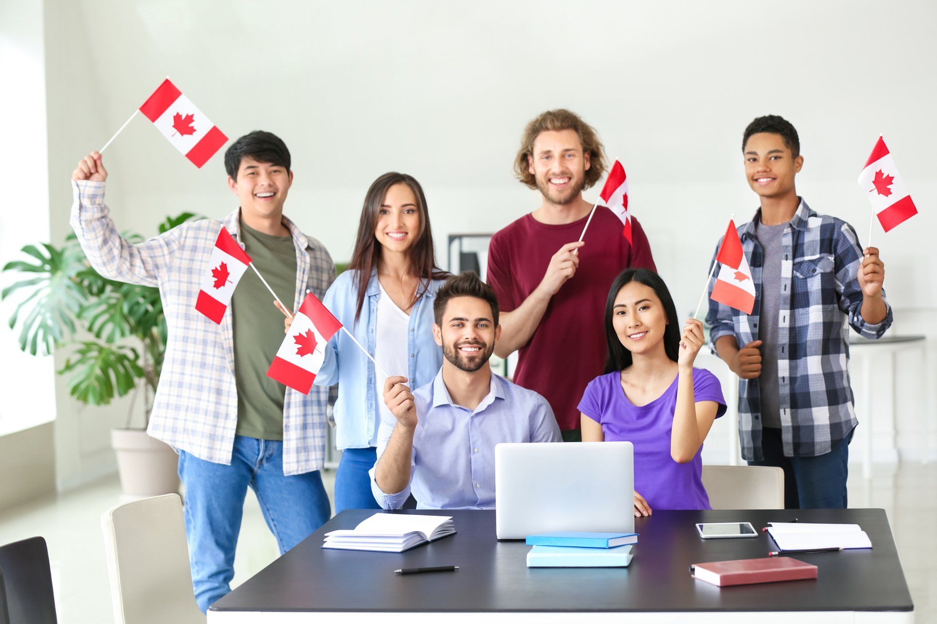 A group of people are standing around a table holding canadian flags.