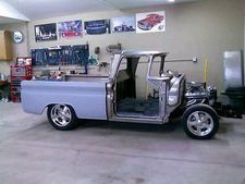 Silver classic pickup truck in a garage, with the body removed and open cab exposed.