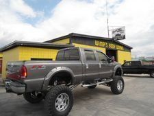 Gray lifted pickup truck parked outside a yellow auto shop