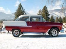 Red and white classic car parked on snow with mountains in the background