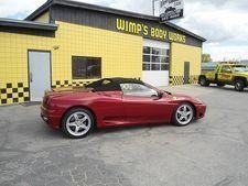 Red convertible sports car parked outside Wimps Body Works auto shop