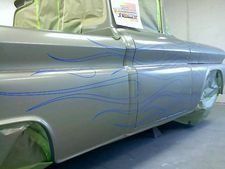 Silver custom car with blue flame decals in a garage