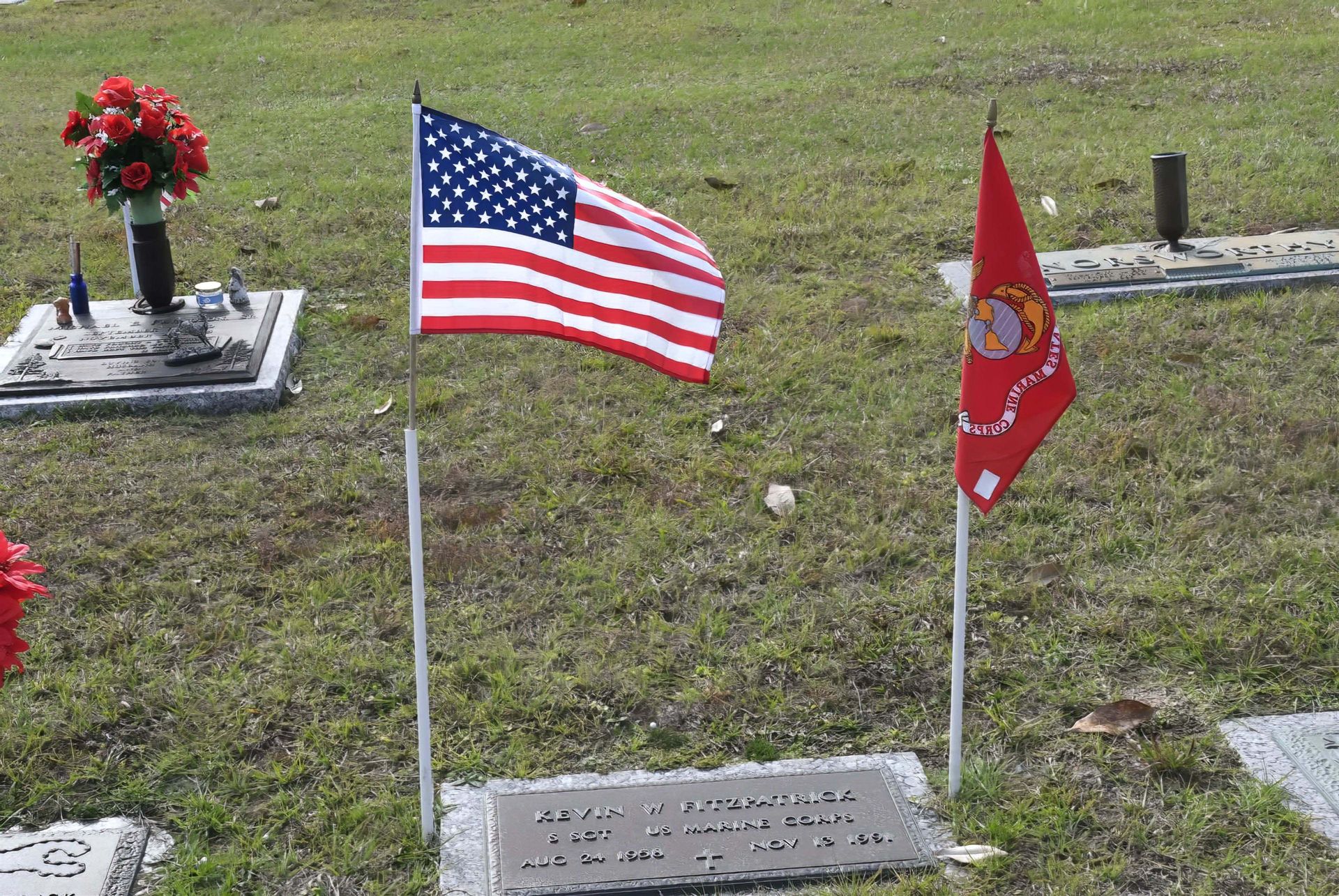 A cemetery with flags and flowers on the graves