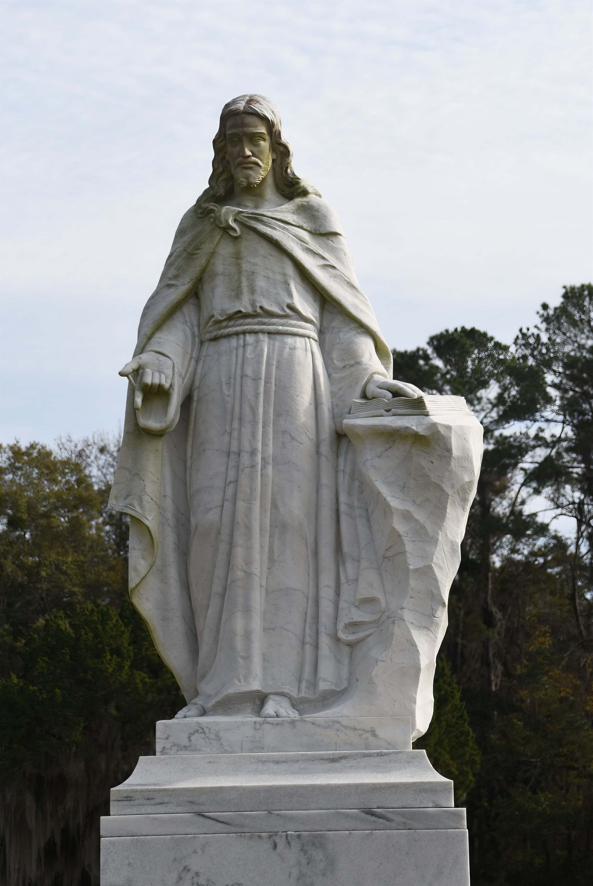 A statue of jesus is standing in a cemetery