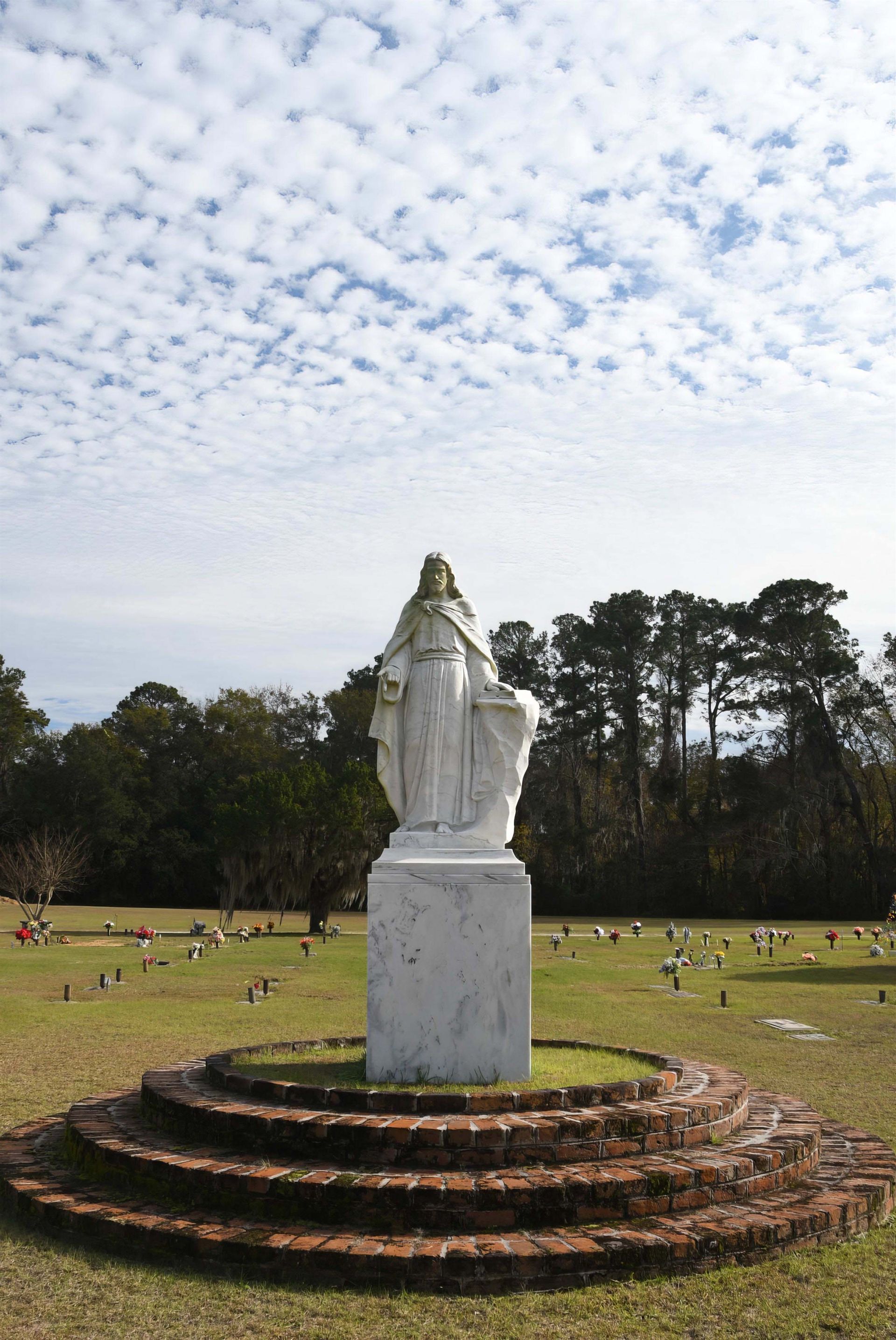 A statue of jesus is in the middle of a cemetery