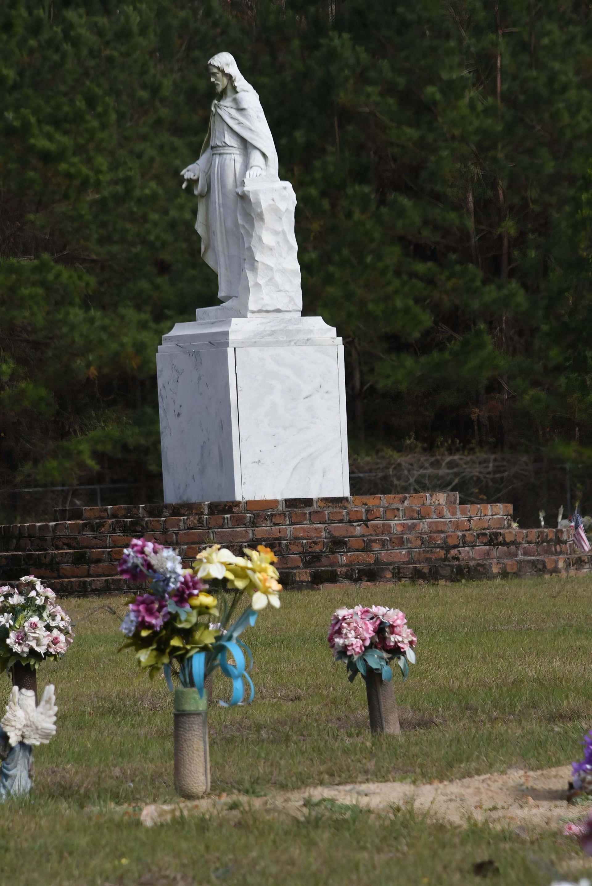 A cemetery with flowers and a statue in the background