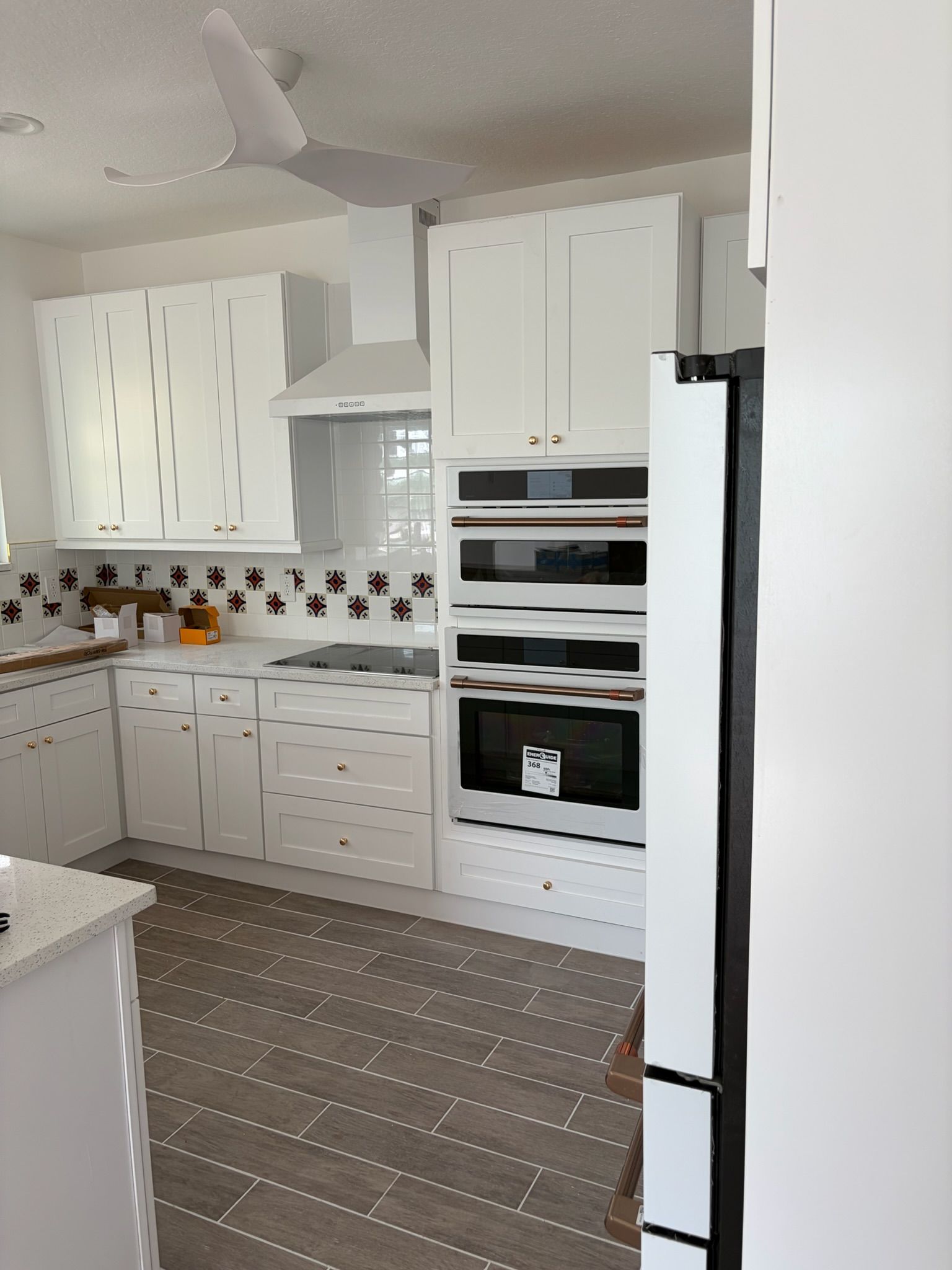 Bright white modern kitchen with built-in ovens, cabinets, and patterned tile backsplash