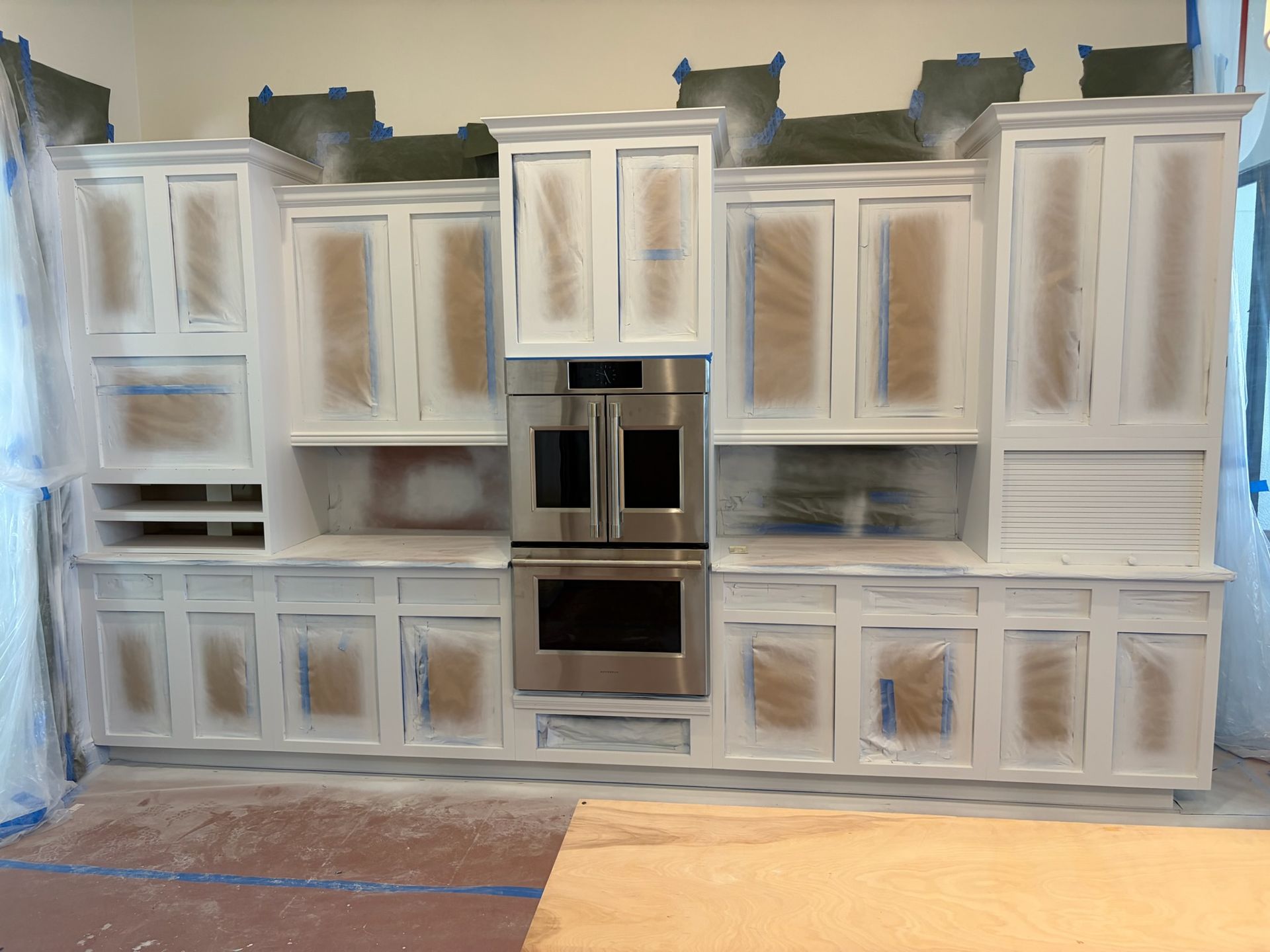 Large white kitchen cabinet wall with built-in stainless steel oven and microwave, unfinished installation