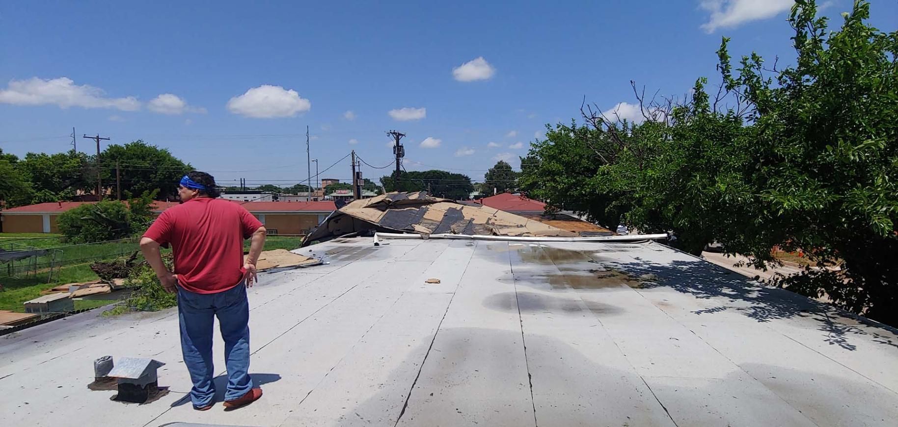 Man standing on a damaged concrete road with cracks and debris under a blue sky