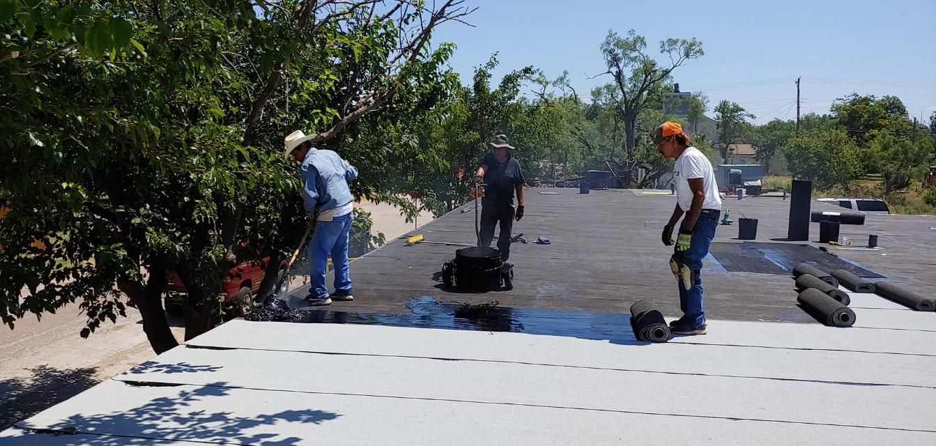 Workers installing rooftop solar panels on a flat roof in bright sunlight
