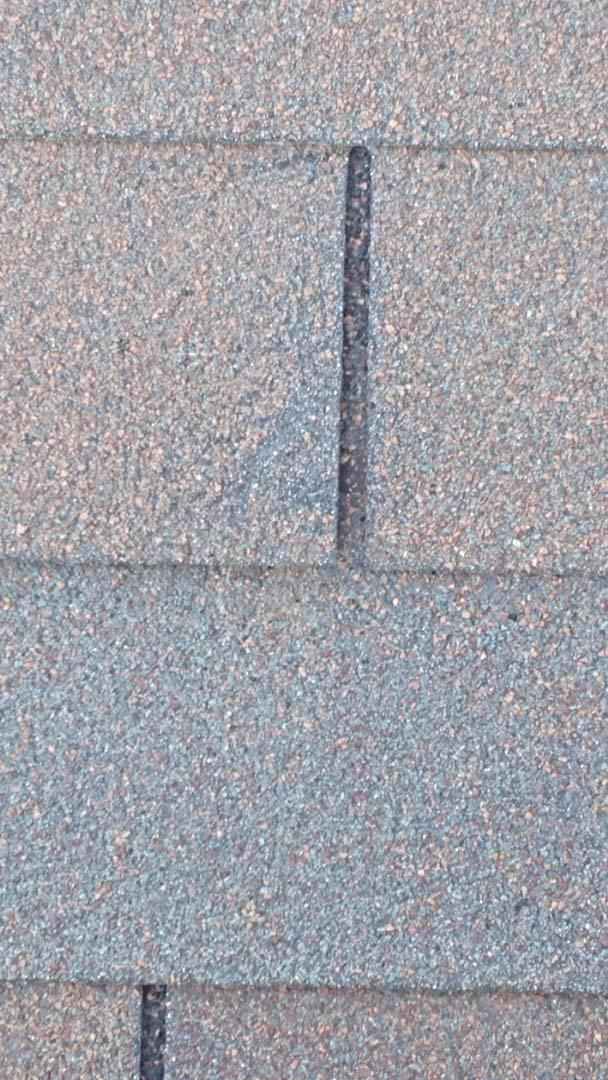 Close-up of gray roof shingles with a vertical seam or flashing line
