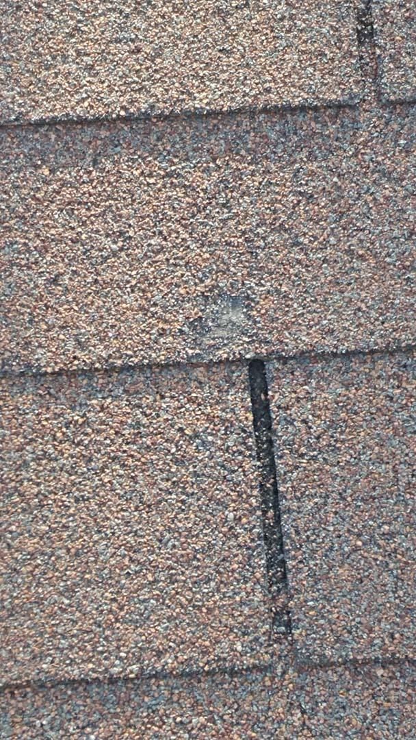 Close-up of gray asphalt roof shingles with a visible vertical seam.