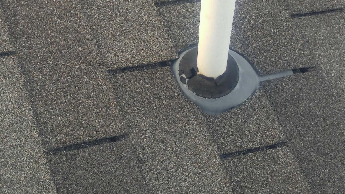 Roof shingles with a white vent pipe and dark flashing collar