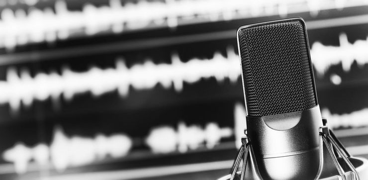 Close-up of a studio microphone with blurred audio waveform in the background