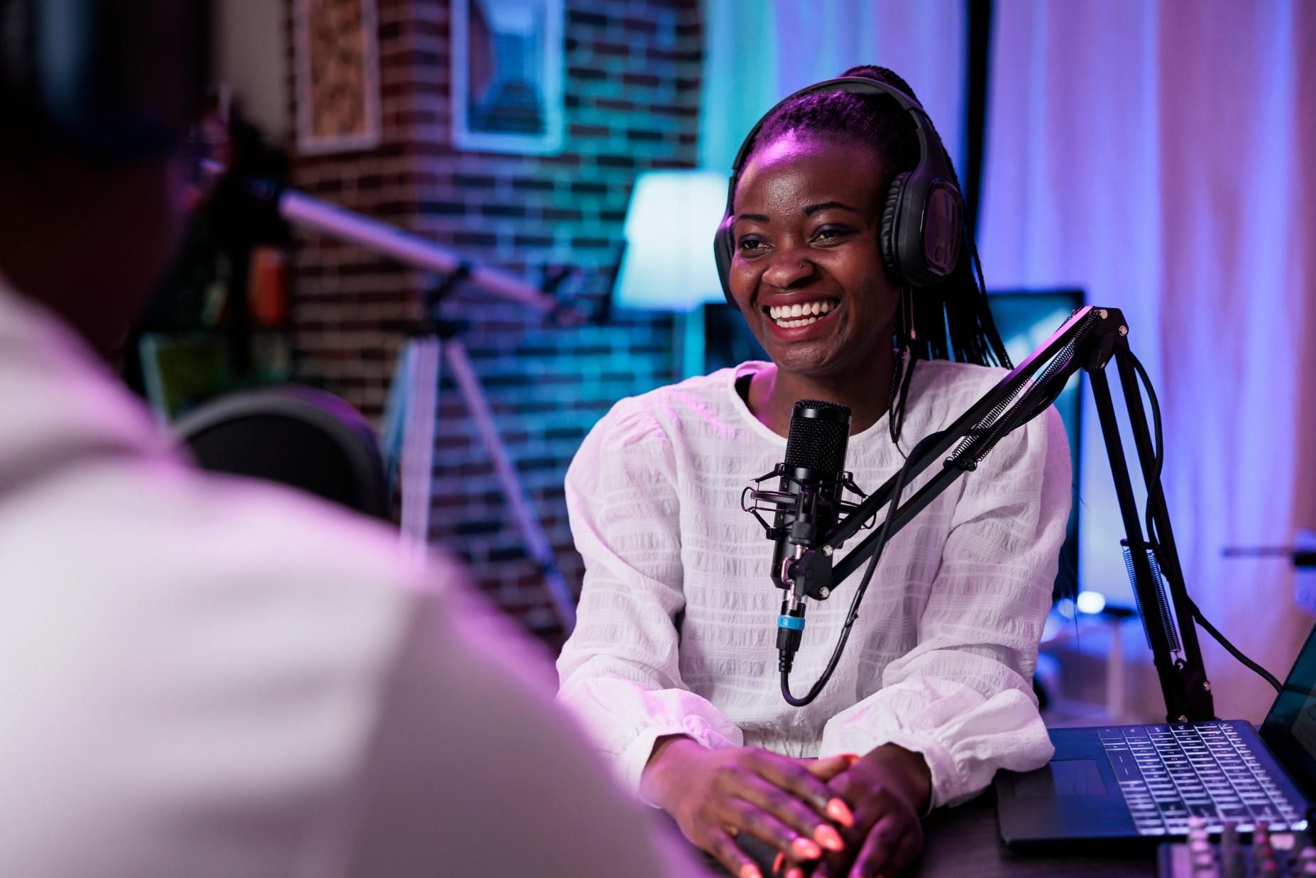 Smiling woman speaking into a studio microphone with headphones on