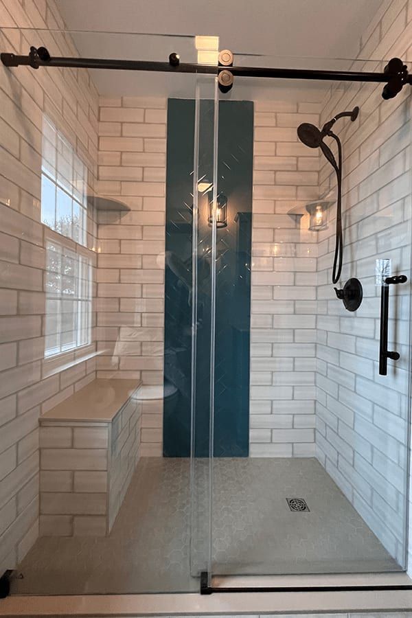 A bathroom with white tiles and a sliding glass shower door.