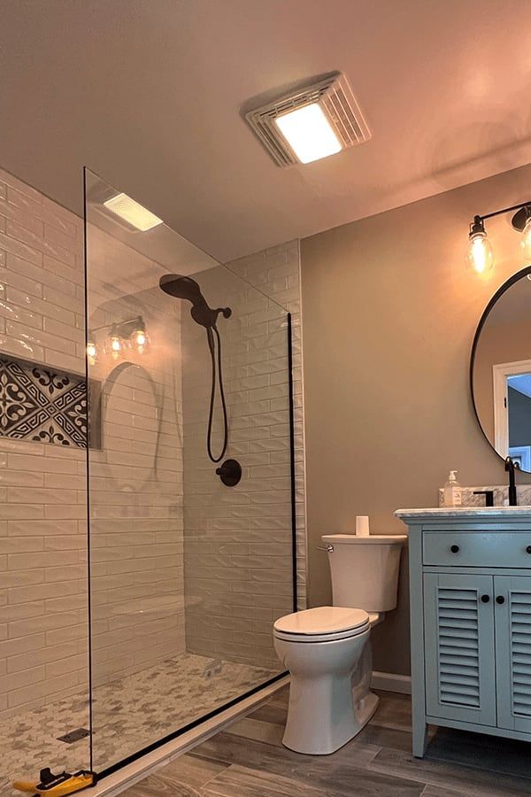 A bathroom with a toilet , sink , shower and mirror.