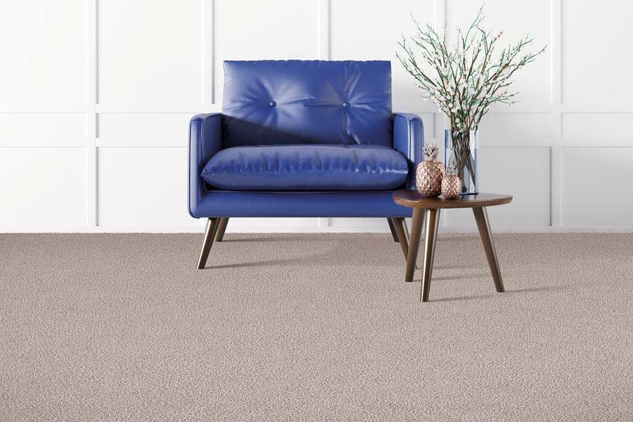 A blue chair is sitting next to a small table in a living room.