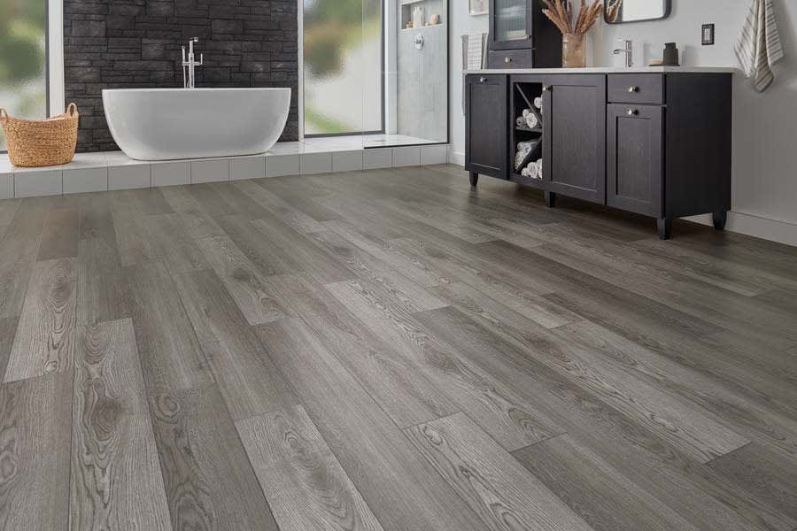 A bathroom with a bathtub , sink , cabinets and hardwood floors.