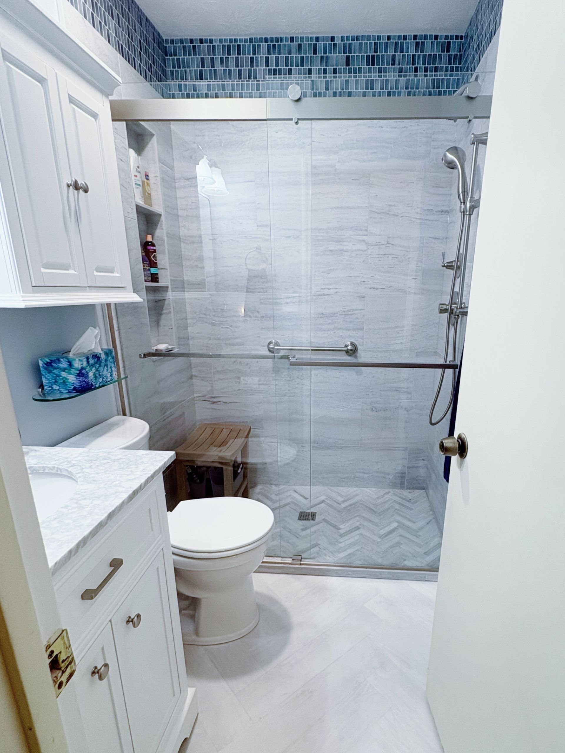 A kitchen with white cabinets , stainless steel appliances , a sink , and a refrigerator.