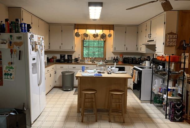 A kitchen with white cabinets and a large island in the middle