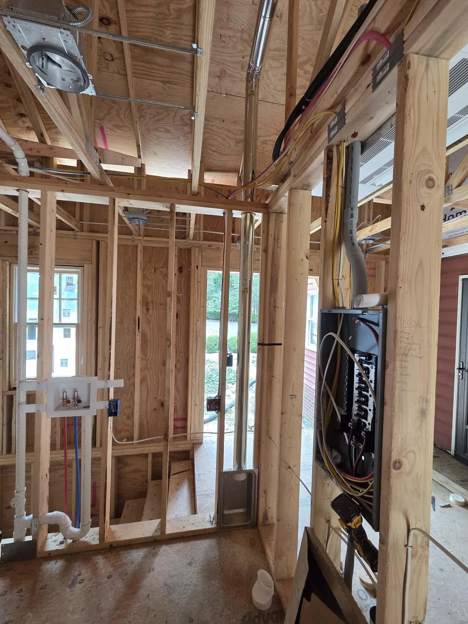 Framed house interior under construction with exposed wiring, studs, and window openings
