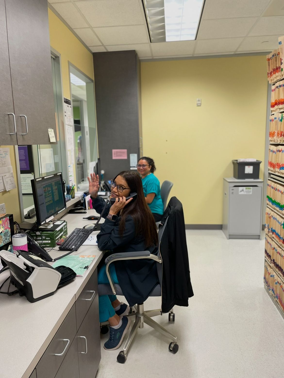 Woman in a pediatric clinic with medical supplies and files.