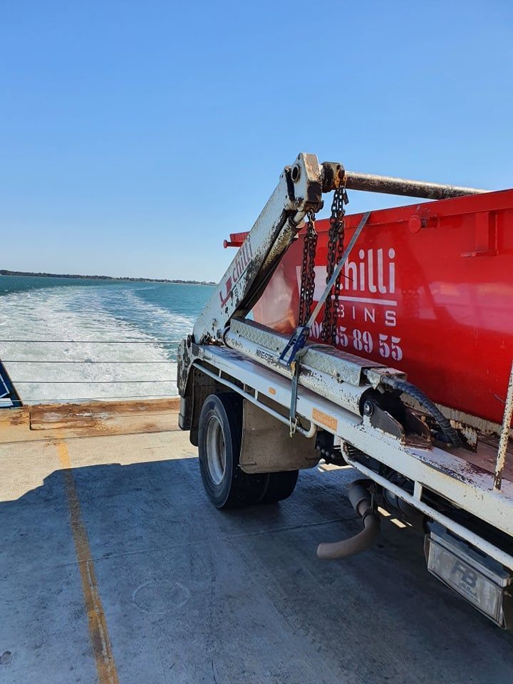 Red Dumpster on Truck On Ferry — Chilli Bins Skip Bins in Caboolture, QLD