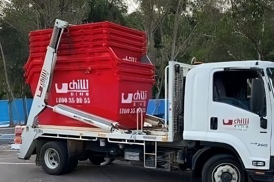 A Dump Truck with A Red Bin on The Back Is Parked in A Parking Lot — Chilli Bins Skip Bins in Glenview, QLD