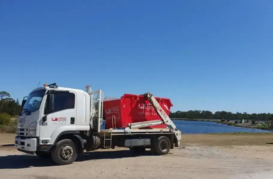 A House Under Construction with A Red Dumpster in Front of It — Chilli Bins Skip Bins in Glenview, QLD