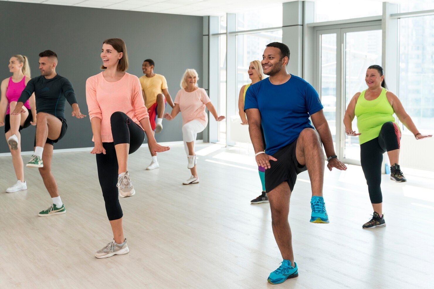 Group in an exercise class, doing high knees, in a bright studio.