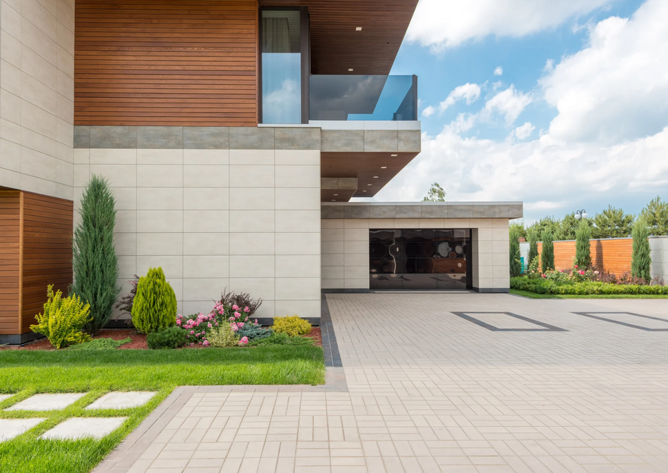 Modern house exterior with wood and stone facade, driveway, and landscaped front yard