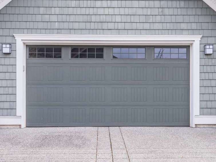 A gray garage door is on the side of a house.