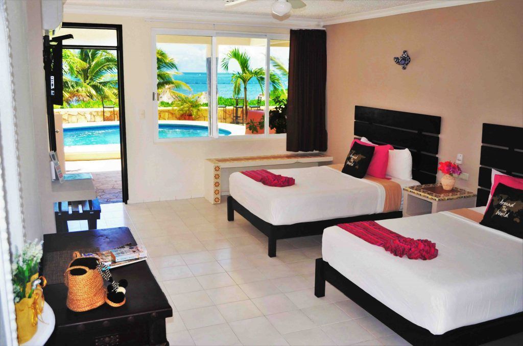 Hotel room with two beds, ocean view, and pool access.
