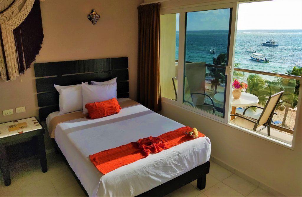Bedroom with a bed, ocean view, and balcony with chairs.