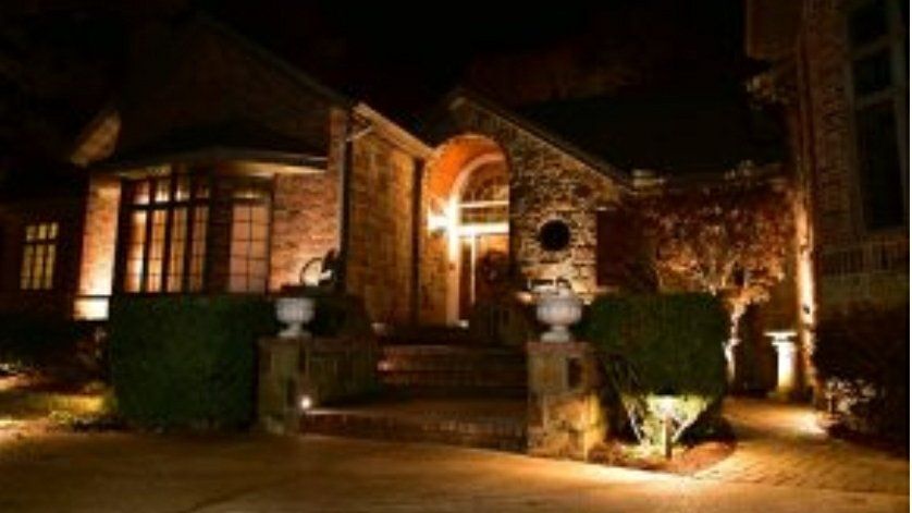 Night view of a brick house with outdoor lighting, focused on the entrance.