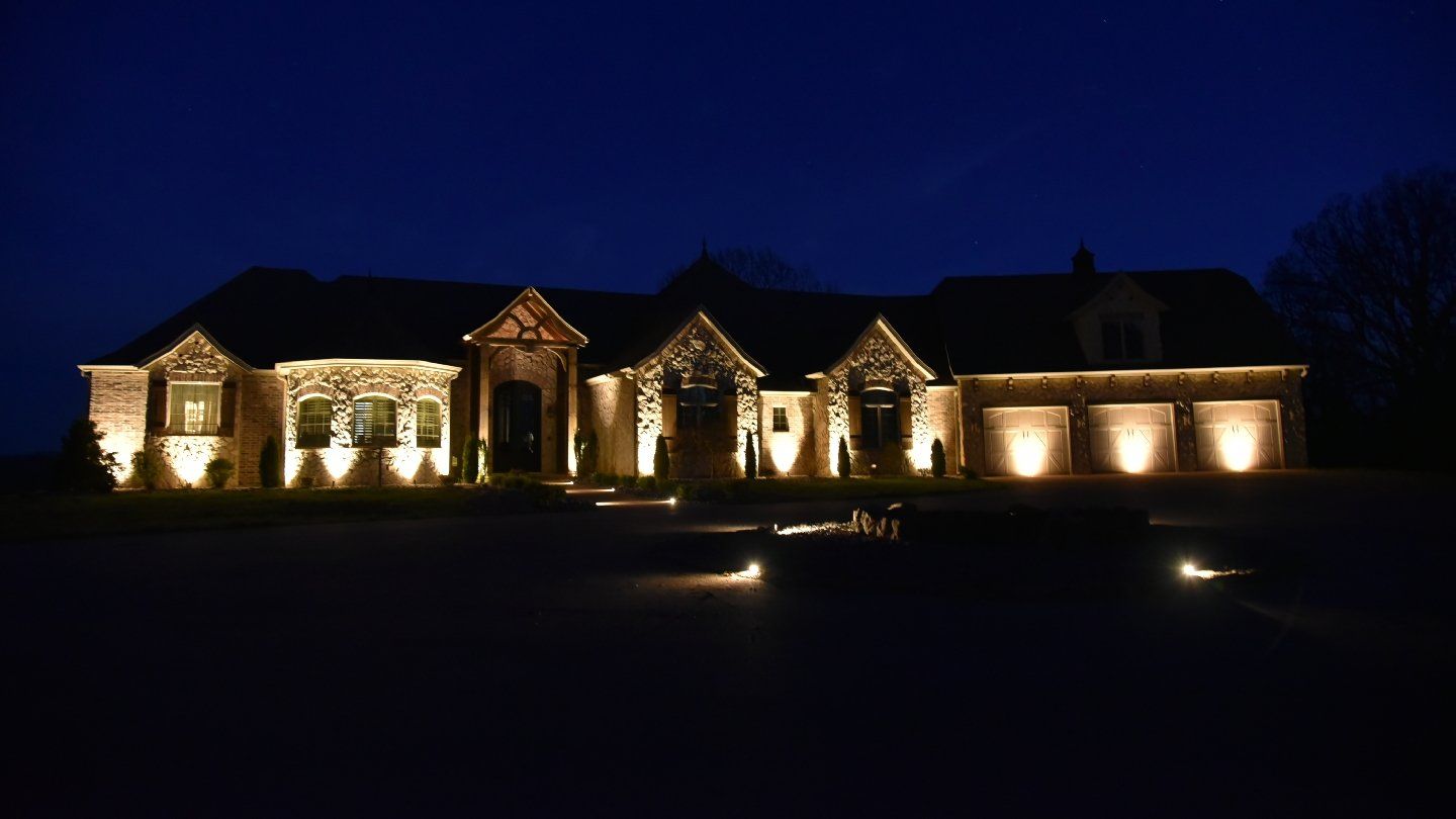 Large house illuminated at night by landscape lighting.