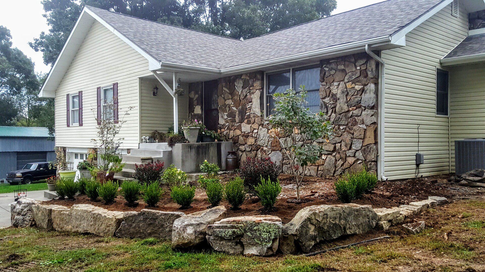 House with stone facade and landscaped front yard with rock retaining wall.