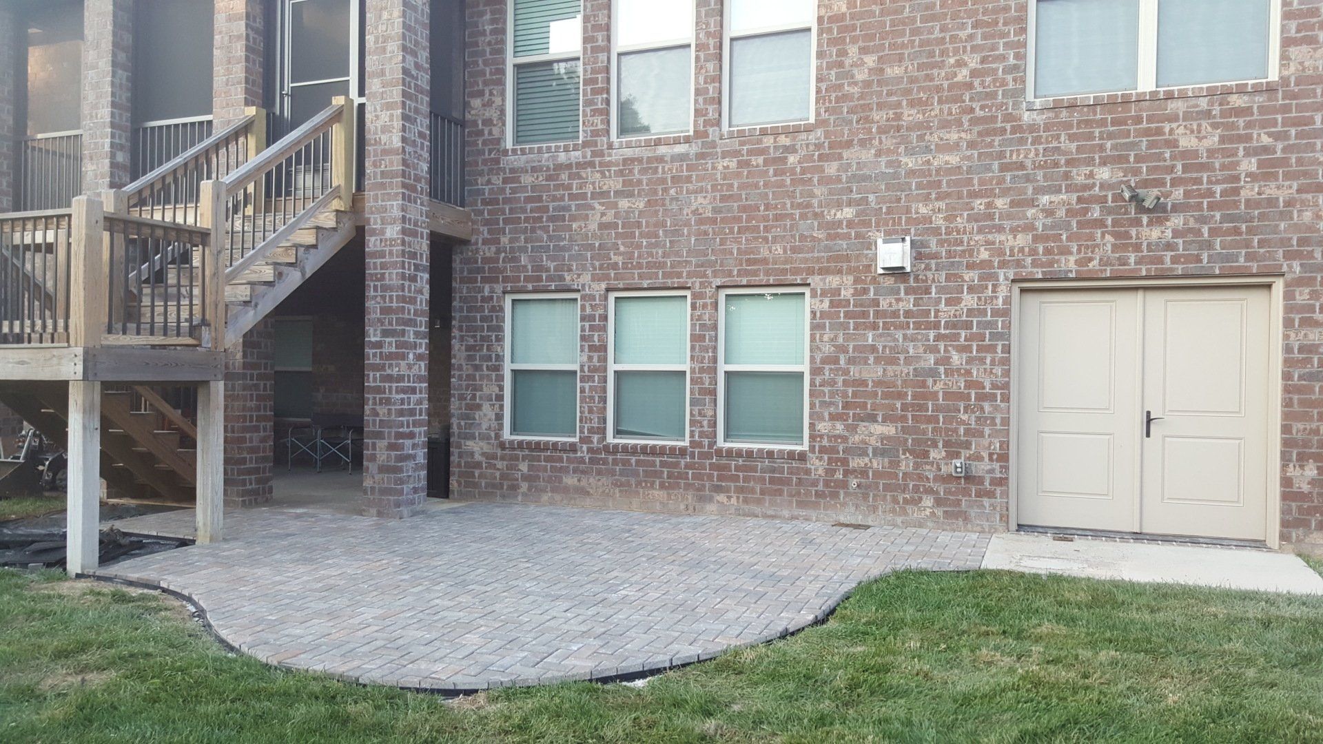 Backyard with brick house, gravel patio, wooden stairs, and garage door.