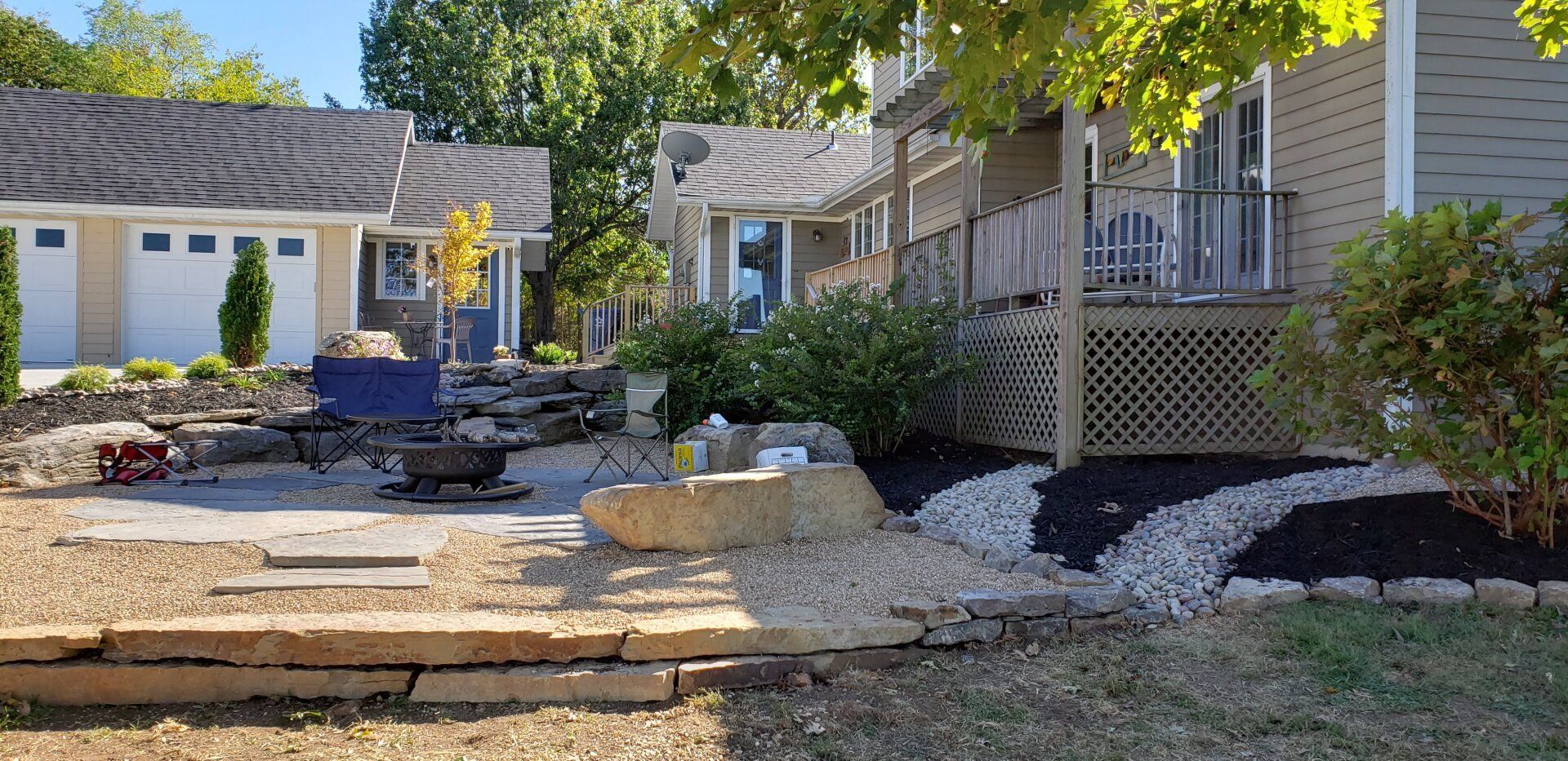 Exterior view of houses with landscaped yards and a stone patio.