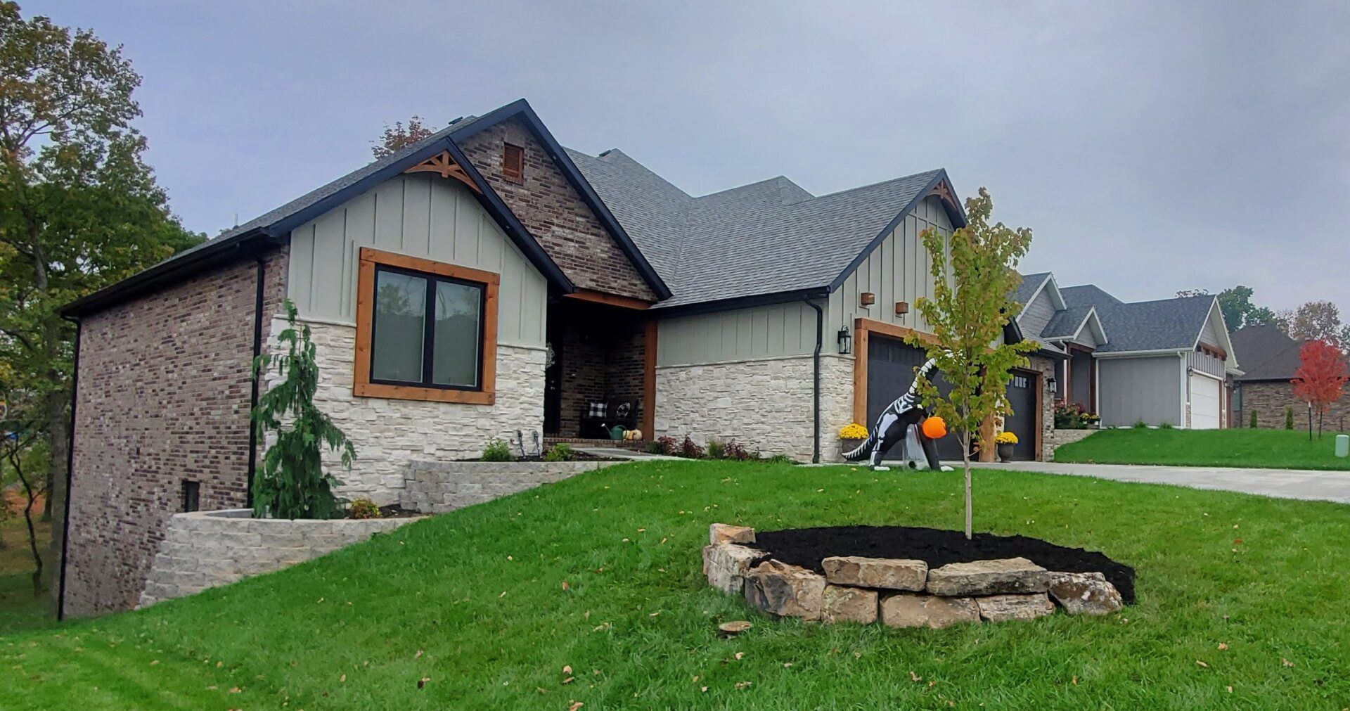 Stone and wood-paneled house with a gray roof and a well-manicured lawn.