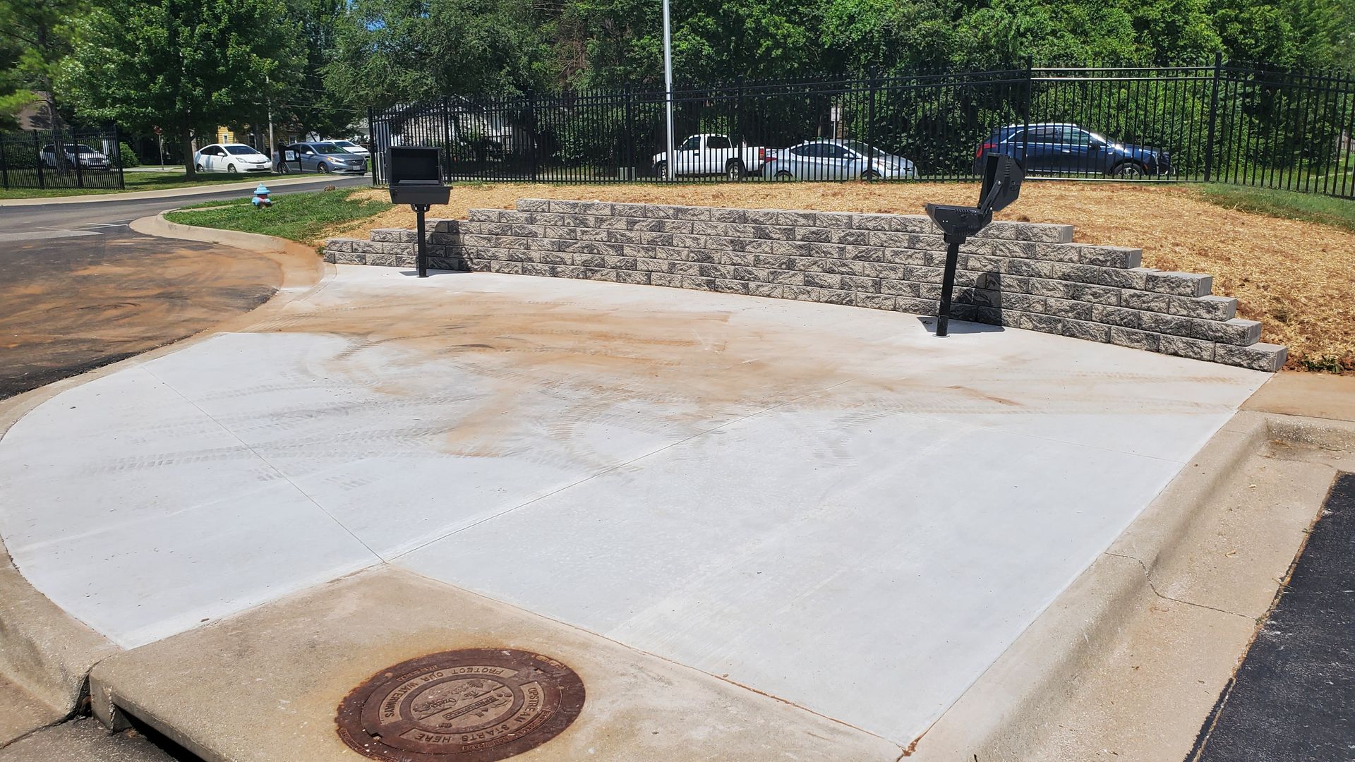 Concrete patio with two grills and a retaining wall.