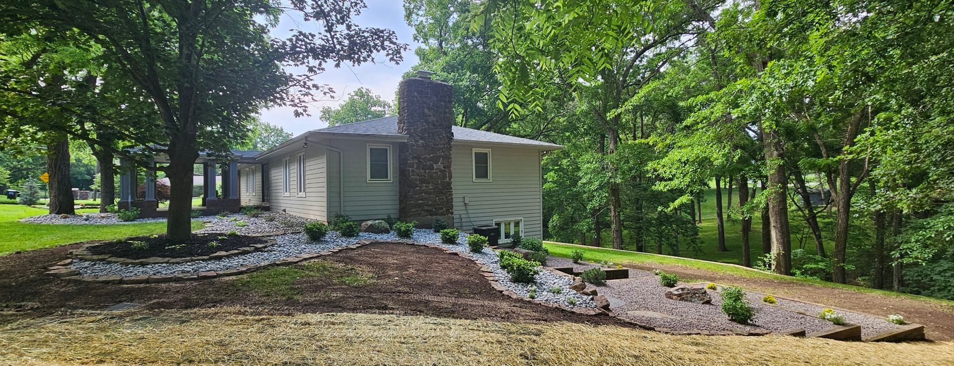 A wooden fence encloses a backyard with a grassy area, small plants, and a stone border.