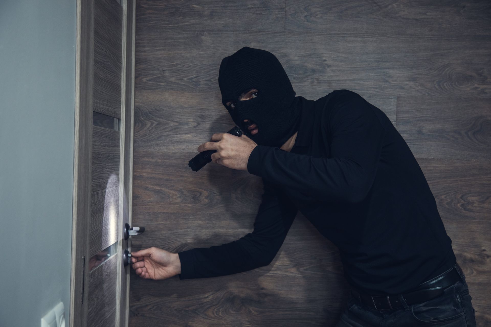A man in a mask is trying to open a door.