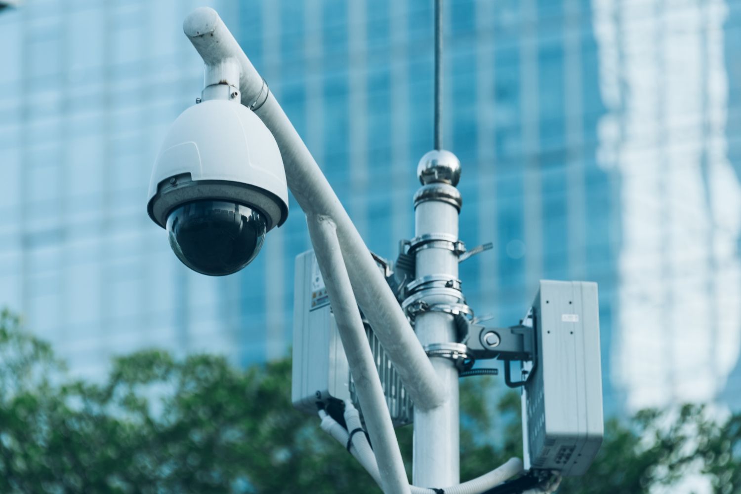 A security camera is sitting on top of a pole in front of a building.