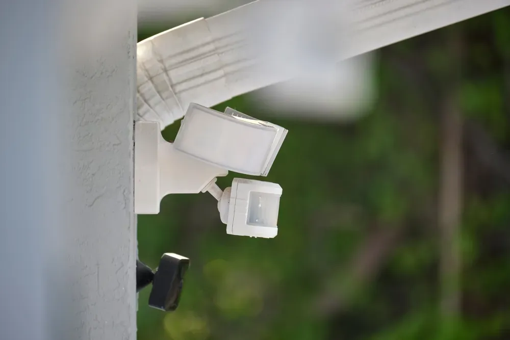 A motion sensor is mounted to the side of a building.