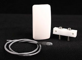 A white device with a cord attached to it is sitting on a black surface.