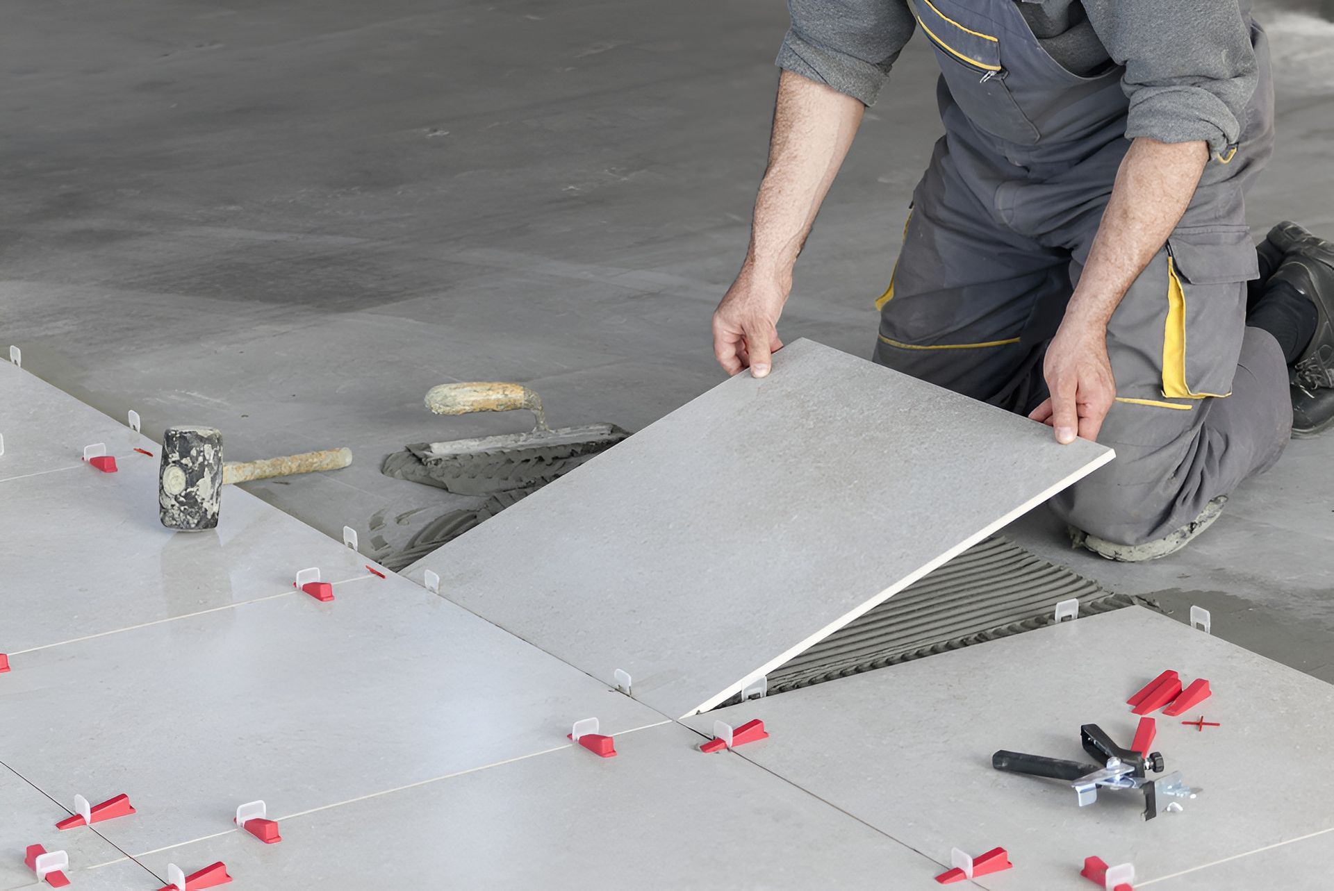 Person Tiling a Floor, Placing a Large Gray Tile — Truecraft Services in Biboohra, QLD